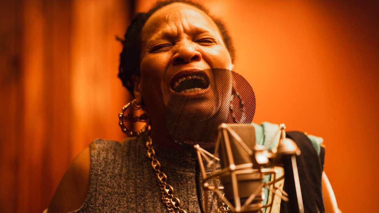 a woman singing into a microphone in a studio